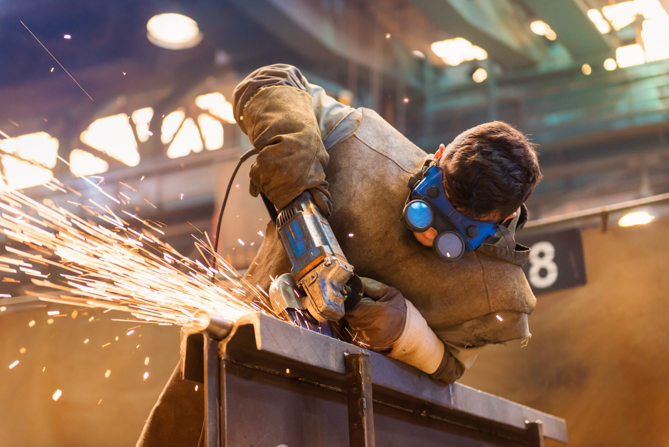 Young,Man,With,Protective,Goggles,Welding,In,A,Factory